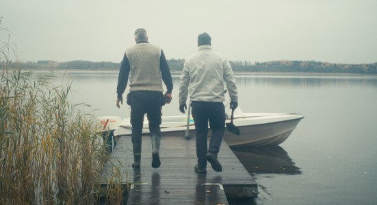 Två personer går på en brygga mot en båt