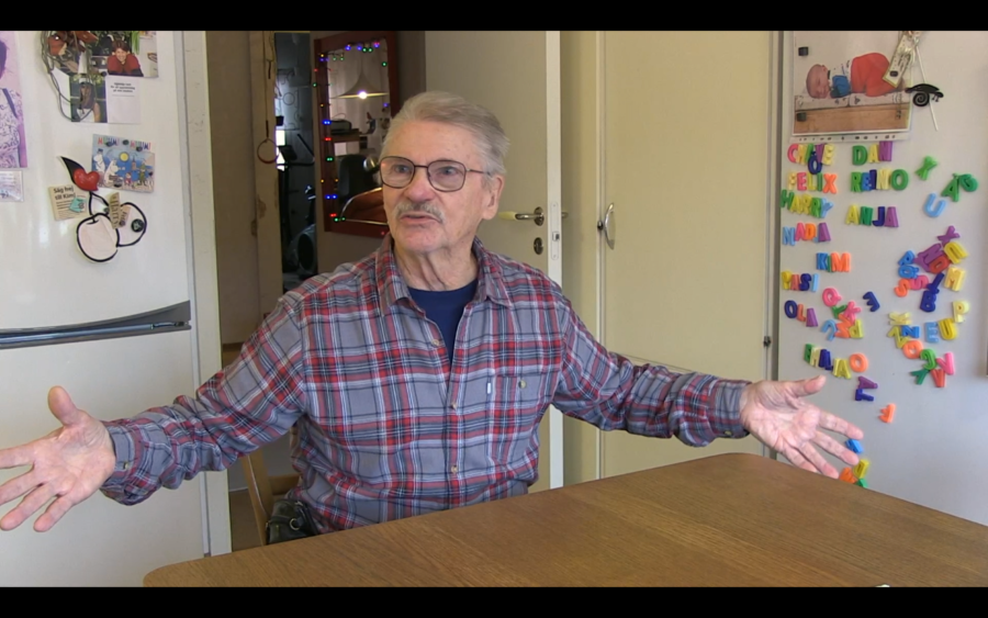 Reino sitter i sitt k&ouml;k, med blicken mot kameran