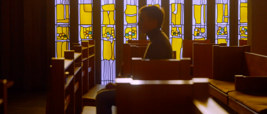 Samppa g&aring;r l&auml;ngst med kyrkob&auml;nkarna. Ljuset str&aring;lar igenom f&ouml;nstret.