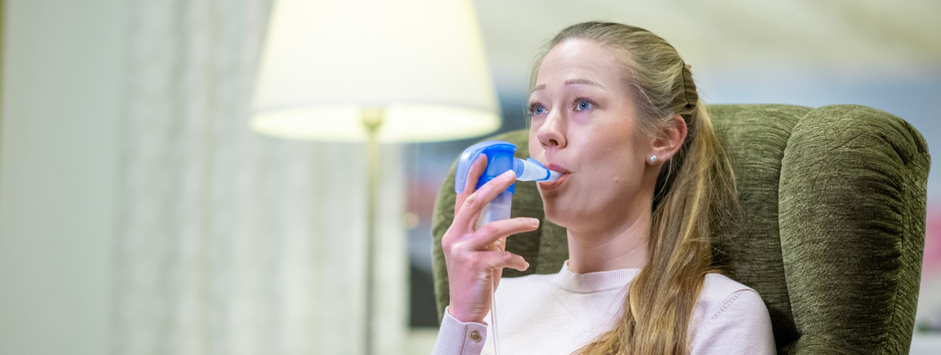 En kvinna andas med hjälp av en inhalator