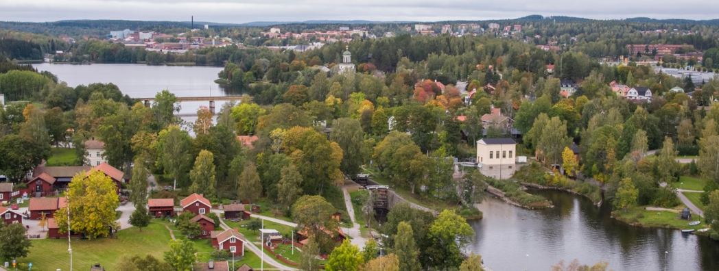 Flygbild där man ser båda skog, vattendrag, hus och trottoarer.