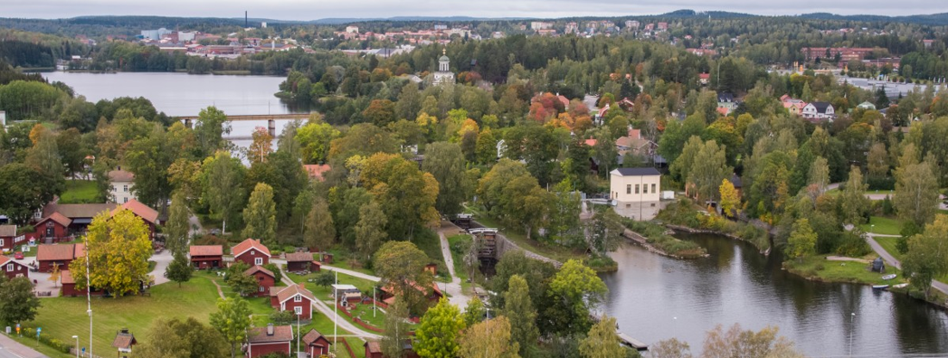 En flygbild över en stad. En å rinner emellan två bostadsområden. Mycket grönska syns.