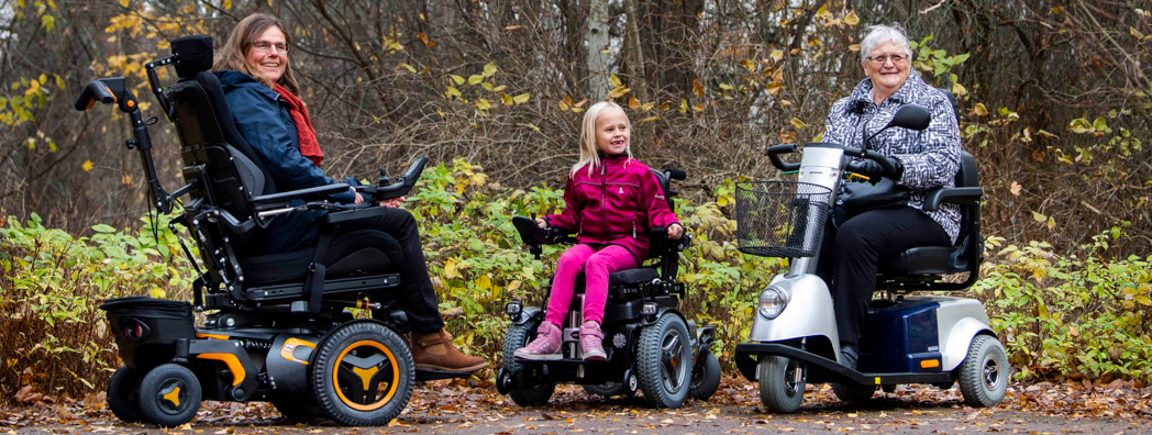 Tre personer i olika åldrar träffas i parken. Alla sitter i varsin elrullstol.