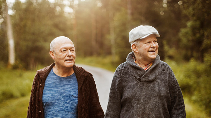 Två äldre män promenerar i skogen