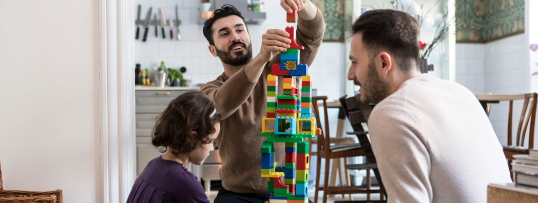 Två pappor leker med sitt barn