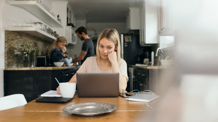 Kvinna sitter och arbetar vid sin dator i hemmamiljö