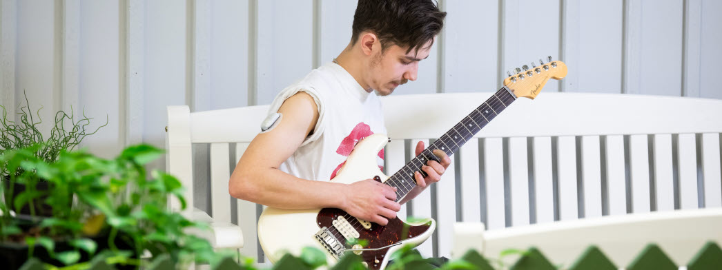 En ung man med insulinpod spelar gitarr