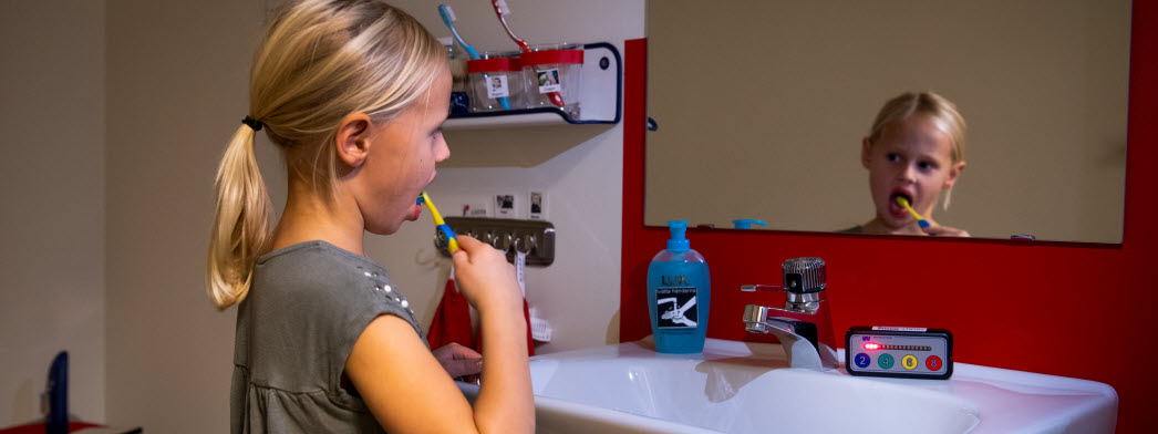 En flicka borstar tänderna och använder en timstock för att få hjälp med tiden