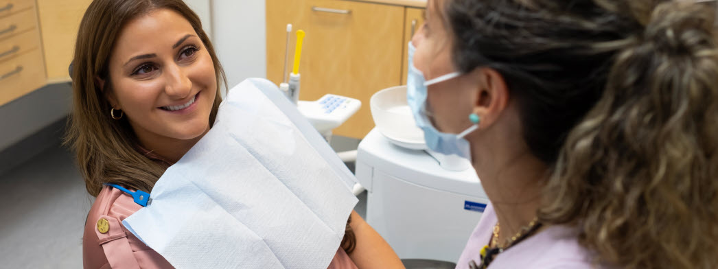 Tandläkare pratar med sin patient under behandling.