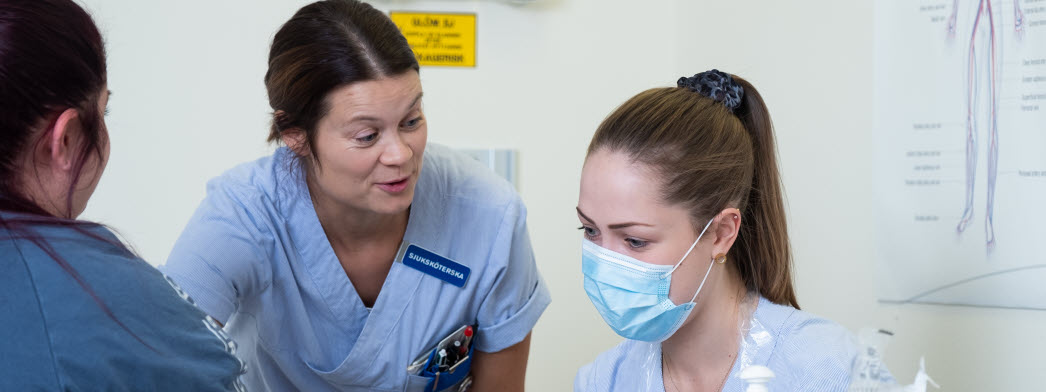 Två sjuksköterskor pratar med en patient. 