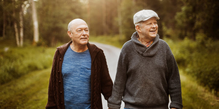 Två äldre män promenerar i skogen