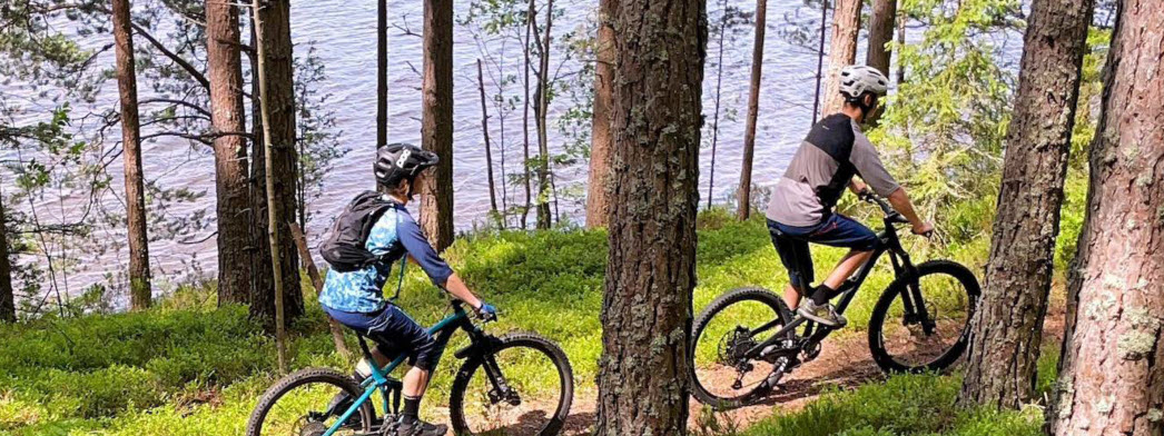 Två personer cyklar i skogen