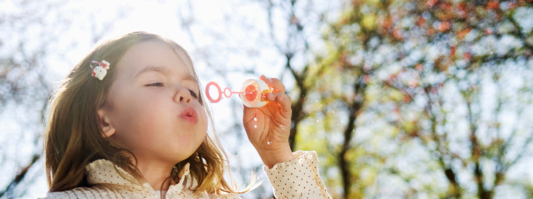 Barn blåser såpbubblor i sommarväder